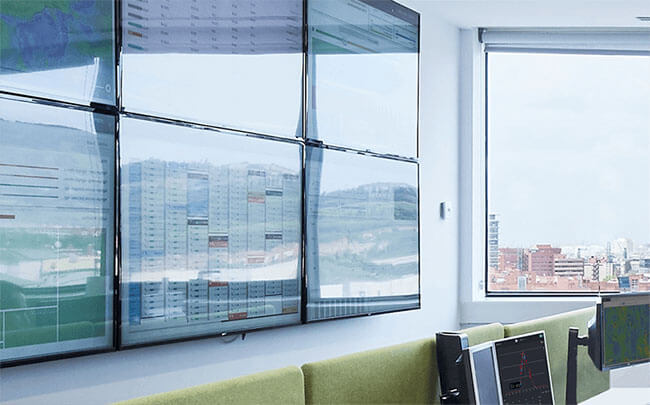 Renewable asset monitoring screens on a wall in a control center.